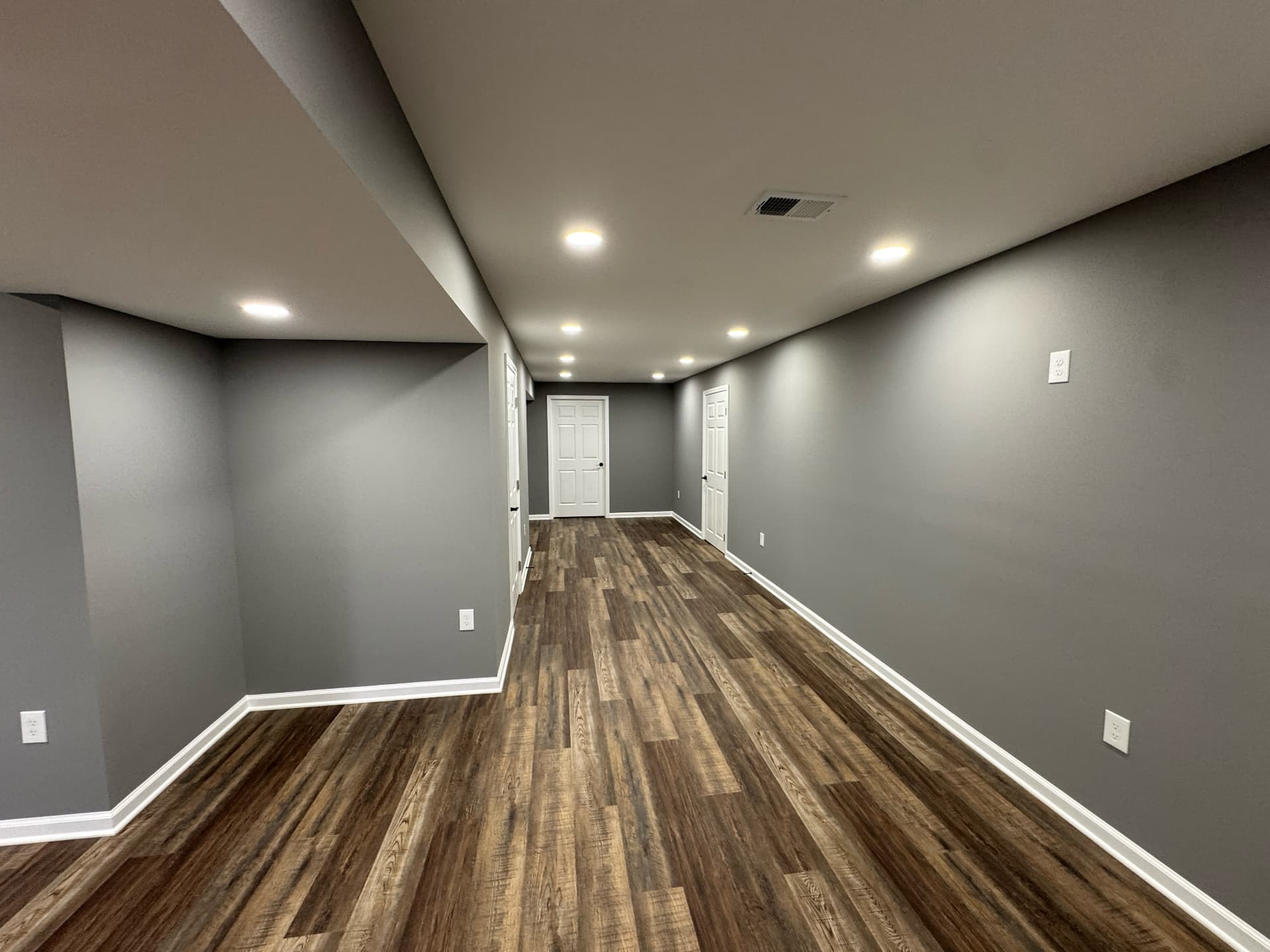 Finished basement corridor with wood-look flooring and fresh trim work