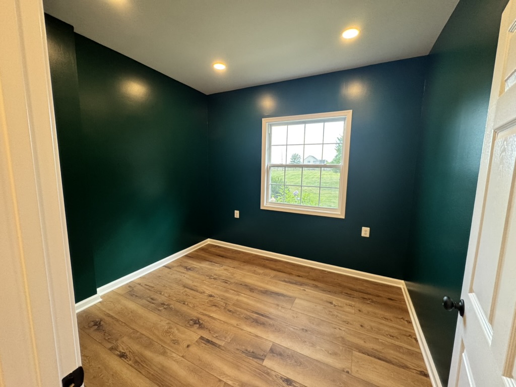 Freshly painted room in deep teal green with new wood-look plank flooring and white trim