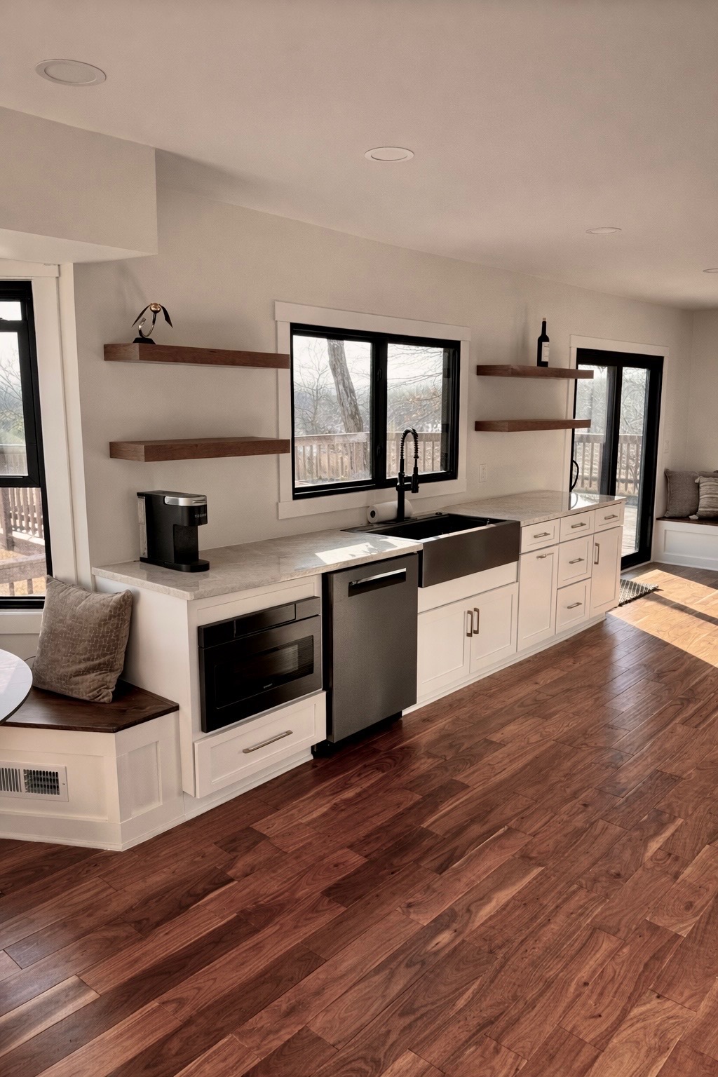 Modern kitchen remodel with white cabinets, floating wood shelves, and a dark farmhouse sink